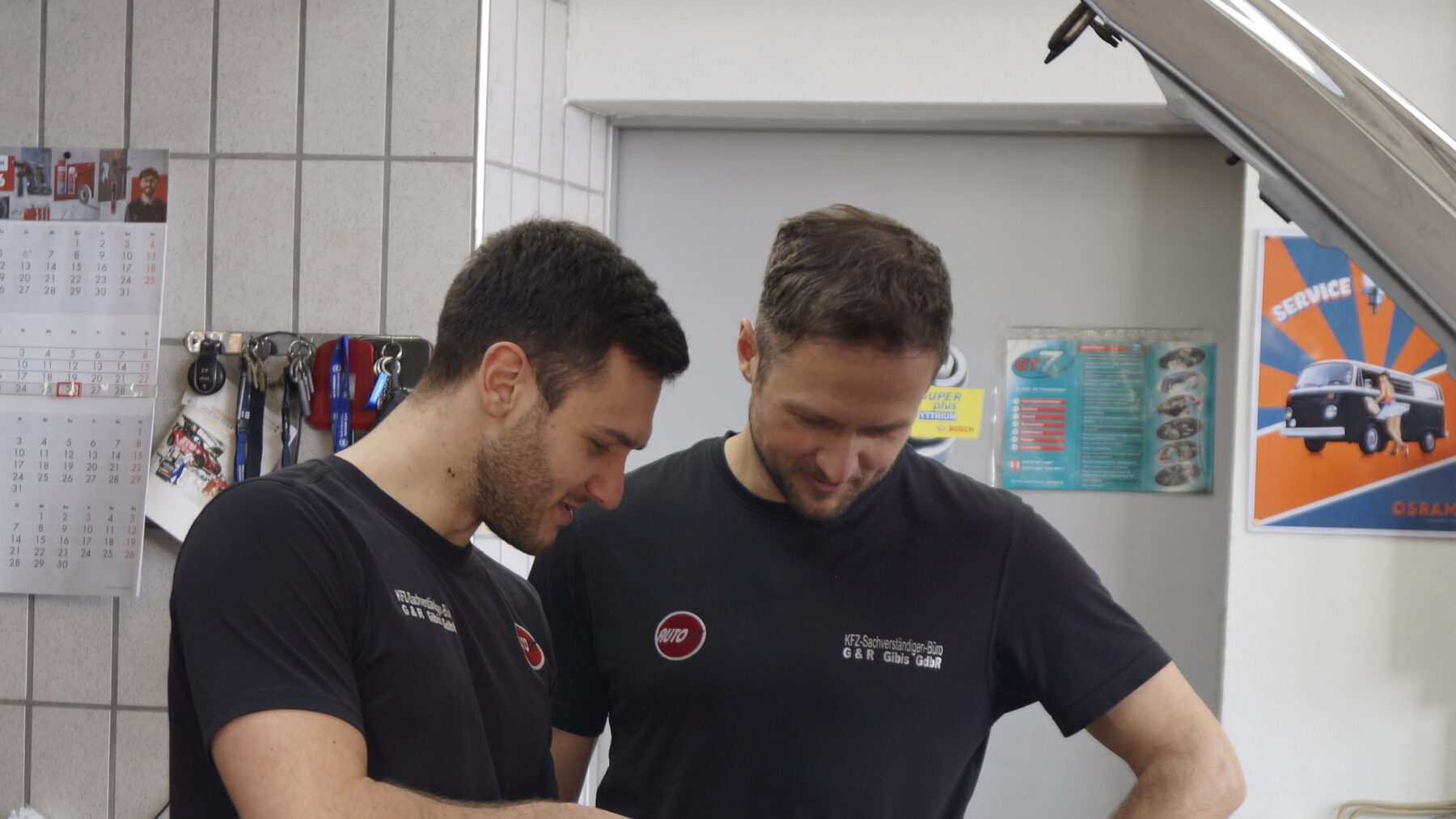 Zwei Mechaniker besprechen eine Reparatur am Fahrzeug